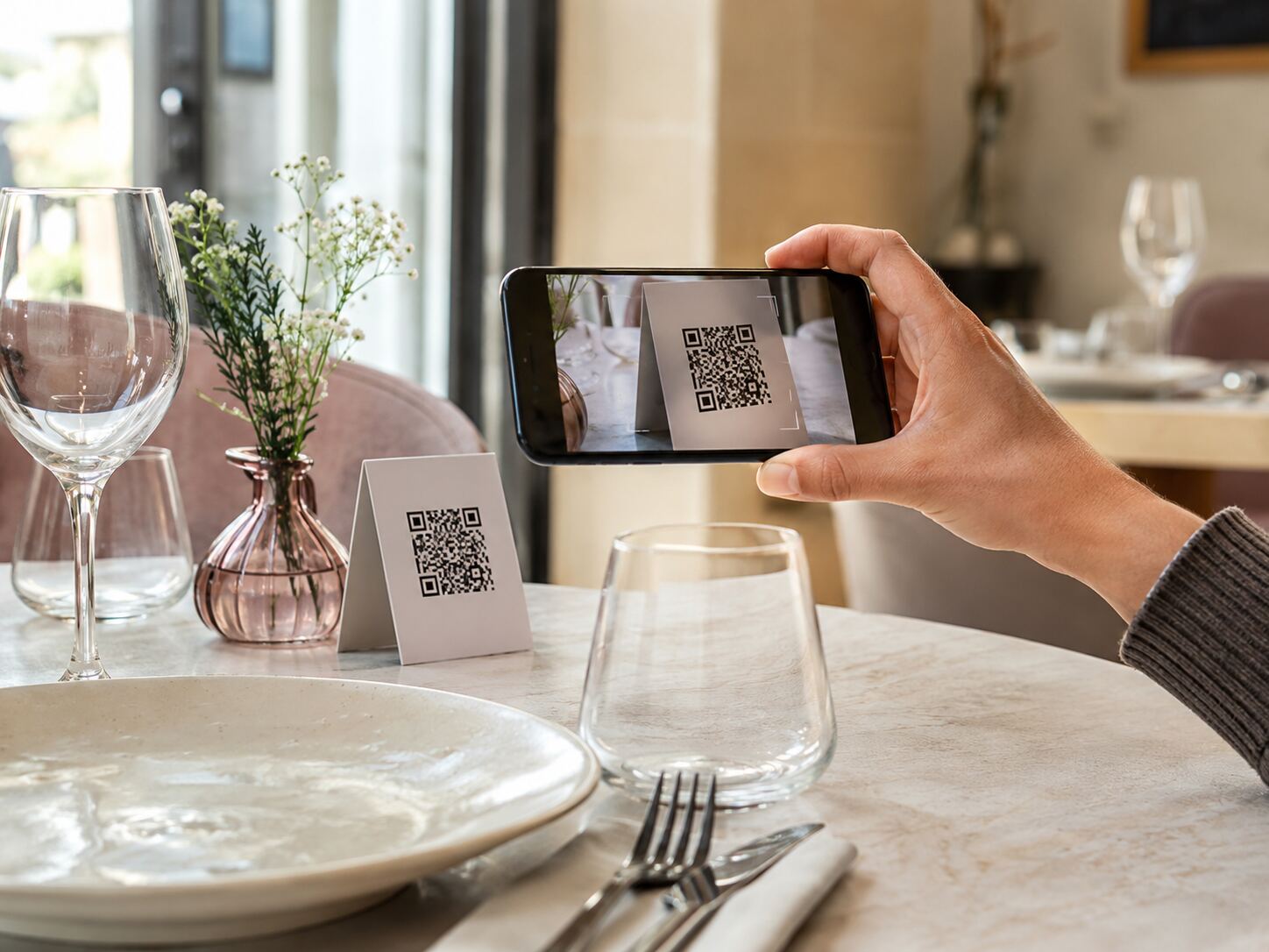 Un téléphone scanne le QR code posé sur une table de restaurant.